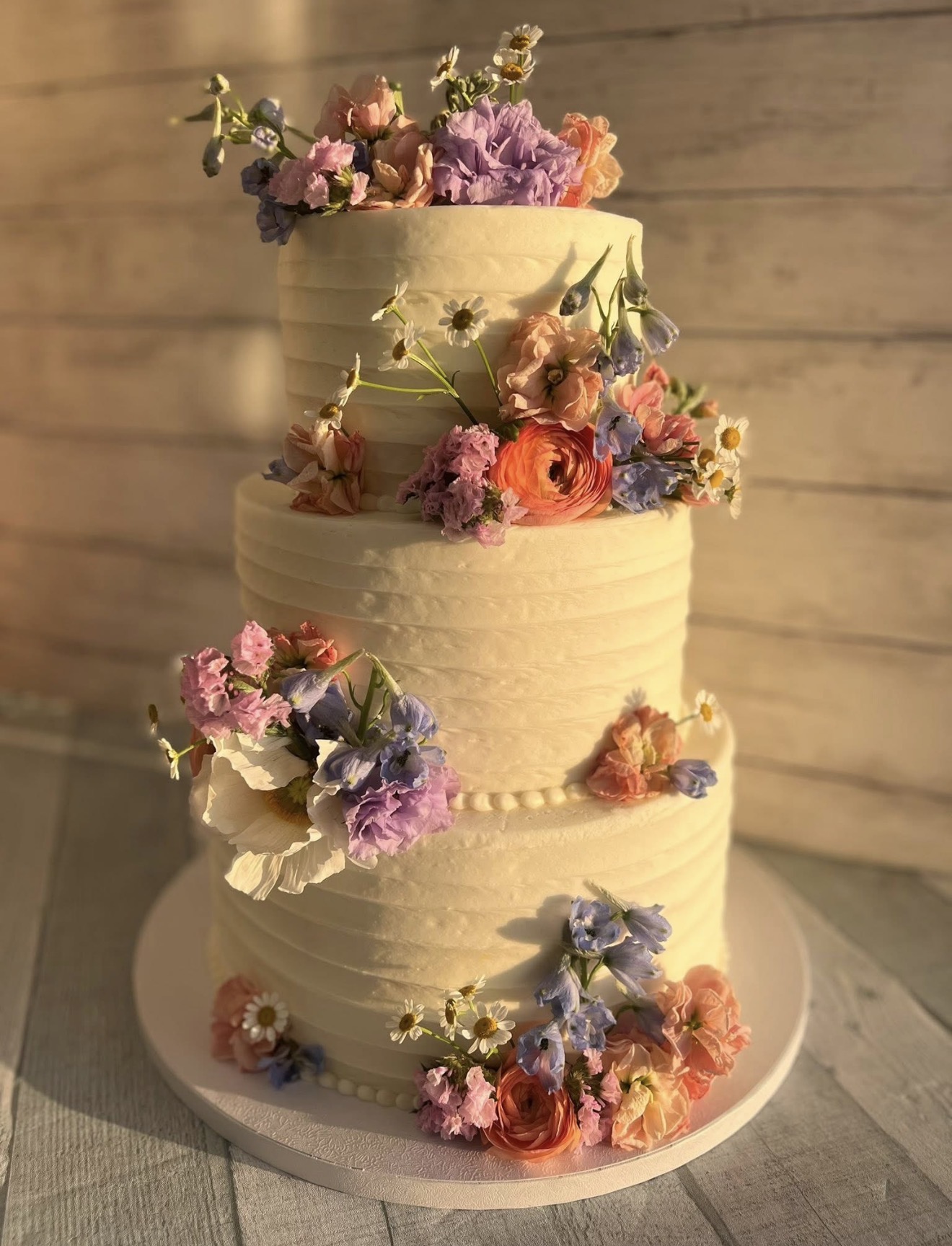 Three-tier white wedding cake decorated with pastel flowers
